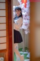 A woman in a sailor outfit standing in front of a door.