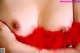 A close up of a woman's breasts with red feathers.