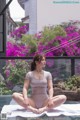 A woman sitting on a yoga mat in front of a pool.